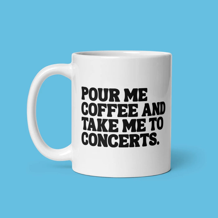 White mug with black words: our me coffee and take me to concerts